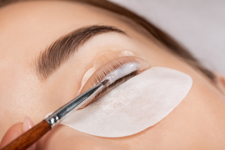 Make-up artist makes the procedure of lamination and dyeing of eyelashes to a beautiful woman in a beauty salon. Eyelash extensions. Eyelashes close-up